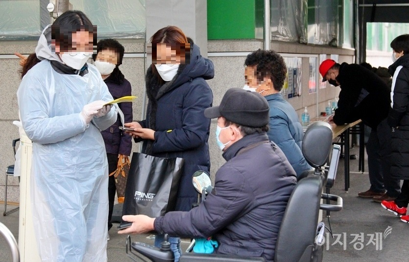 서울 상계백병원 출입구. 병원 직원(왼쪽 첫번째)이 모바일 방명록을 작성한 30대 여성(왼쪽 세번째)과 노부부에게 노란색의 ‘확인’ 딱지를 붙여 주고 있다. 사진 오른쪽은 종이 방명록을 작성하고 있는 내원객들. 사진= 김보람 기자