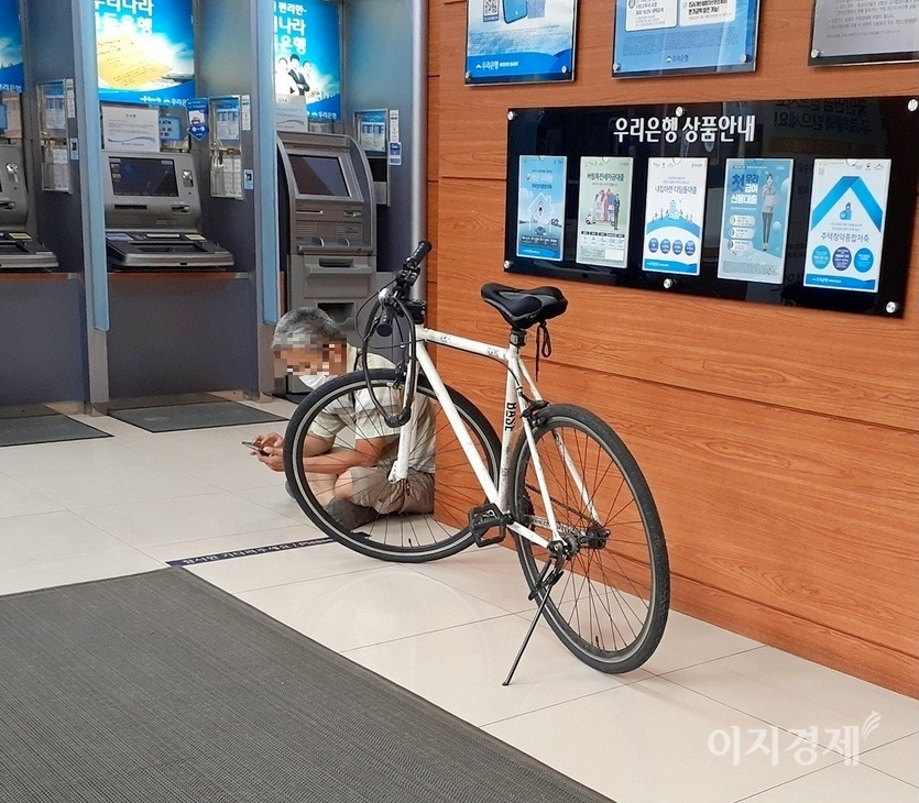 자전거를 타고 가다 지쳤는지, 한 시민이 우리은행 자동화기기 설치 공간으로 들어와 스마트폰 삼매경에 빠졌다. 이날 서울의 낮 최고 기온은 27℃로 다소 무더웠다. 사진=정수남 기자