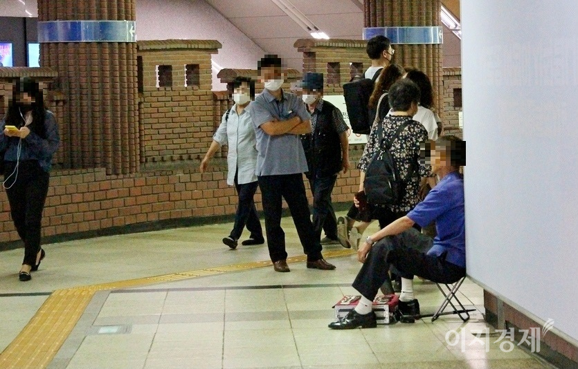 서울지하철공사 직원이 환승통로에서 상행위를 하는 70대 노인에게 철수할 것을 주문했지만, 노인이 이 직원을 애써 외면하면서 버티고 있다. 이 노인은 마스크도 하지않았다. 사진=정수남 기자