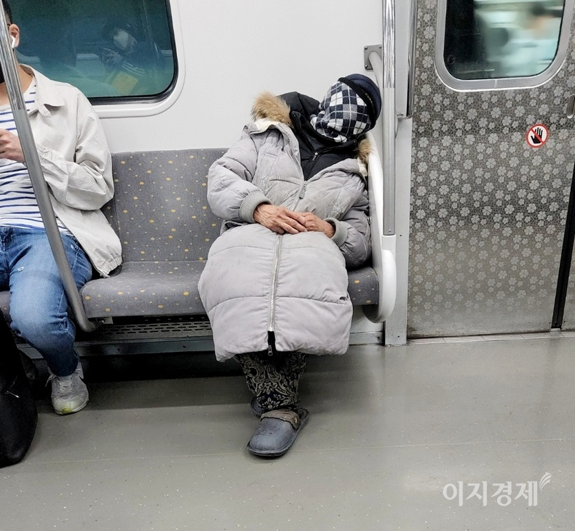 노숙인으로 보이는 한 여자 노인이 두건 등으로 얼굴을 싸맨 채 잠에 떨어졌다. 사진=김진이 기자