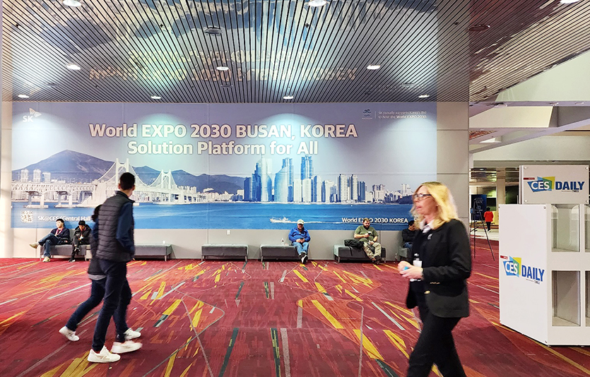SK이노베이션이 라스베이거스 컨벤션 센터안에 설치한 ‘2030 부산엑스포 유치 기원’ 대형 현수막 앞을 관람객들이 지나가고 있다. 사진=SK이노베이션