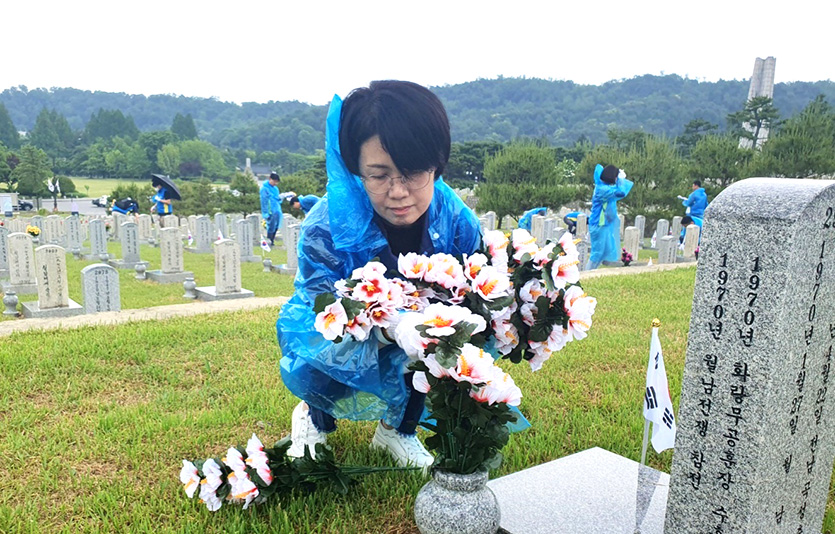  국립서울현충원 봉사활동에 참여한 신한은행 직원이 묘역에 태극기를 꽂고 헌화하는 모습. 사진=신한은행