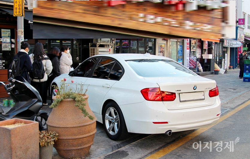 20대로 보이는 4명의 여성이 불법주차한 BMW 320d 4륜 구동을 피해 떢볶이 가게로 향하고 있다. 사진=정수남 기자