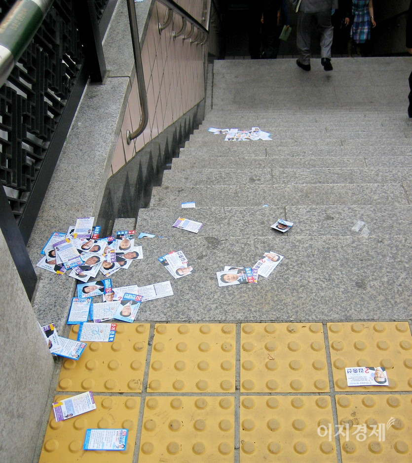 (위부터)2020년 총선 당시 후보자의 현수막과 2006년 지방선거 당시 후보자가 나눠준 명함 크기의 홍보물이 지하철 출입구에 쌓였다. 사진=정수남 기자