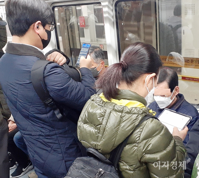 (왼쪽부터)한 남성 승객이 스마트폰으로 뉴스를 보고 있다. 답답하다. 사진=이승렬 기자<br>