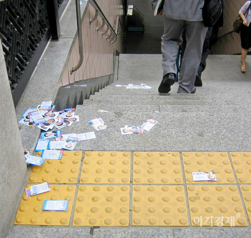 후보자들이 지하철 출구에서 배포한 명함 크기의 홍보물이 어지럽게 버려졌다. 비닐 코팅으로 쓰레기다. 사진= 정수남 기자