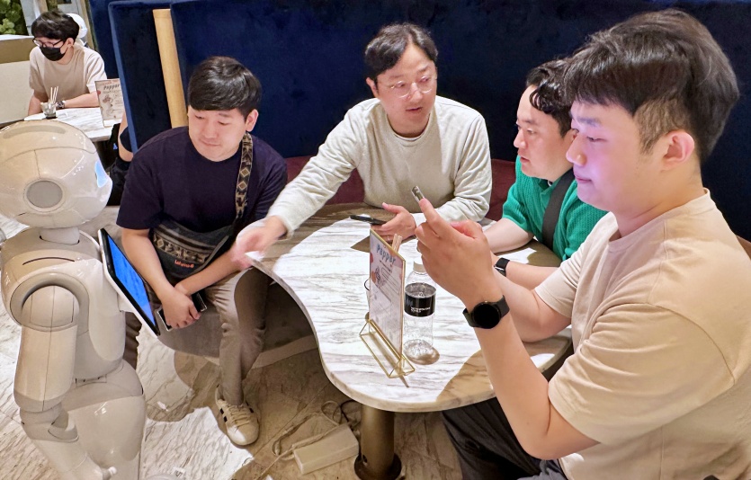 프로그램에 참여한 직원들이 일본 도쿄의 페퍼 팔러 카페에서 서비스 로봇 이용을 체험하고 있다. 사진=LG유플러스